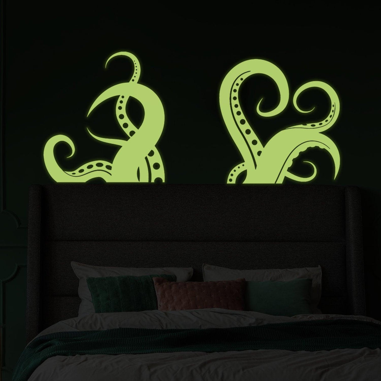 Glow in the dark vinyl octopus tentacle wall art stickers above a bed, adding whimsical decor to a dark room.