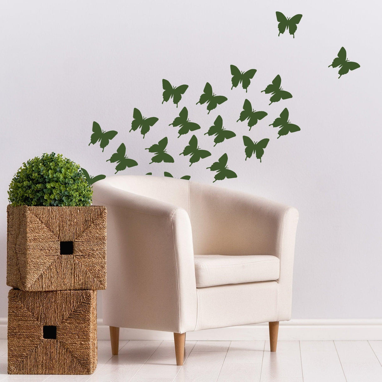 Decorative green butterfly wall stickers flying above a cozy cream chair and woven storage boxes.