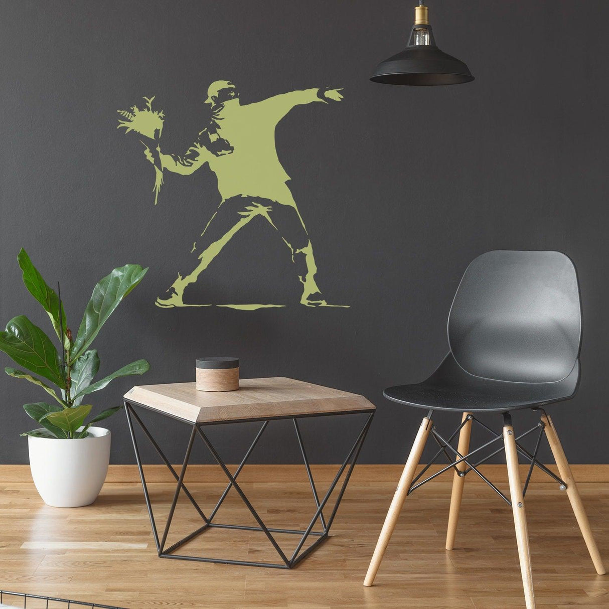 Banksy-inspired flower thrower wall sticker on dark wall in modern living space with chair and table.