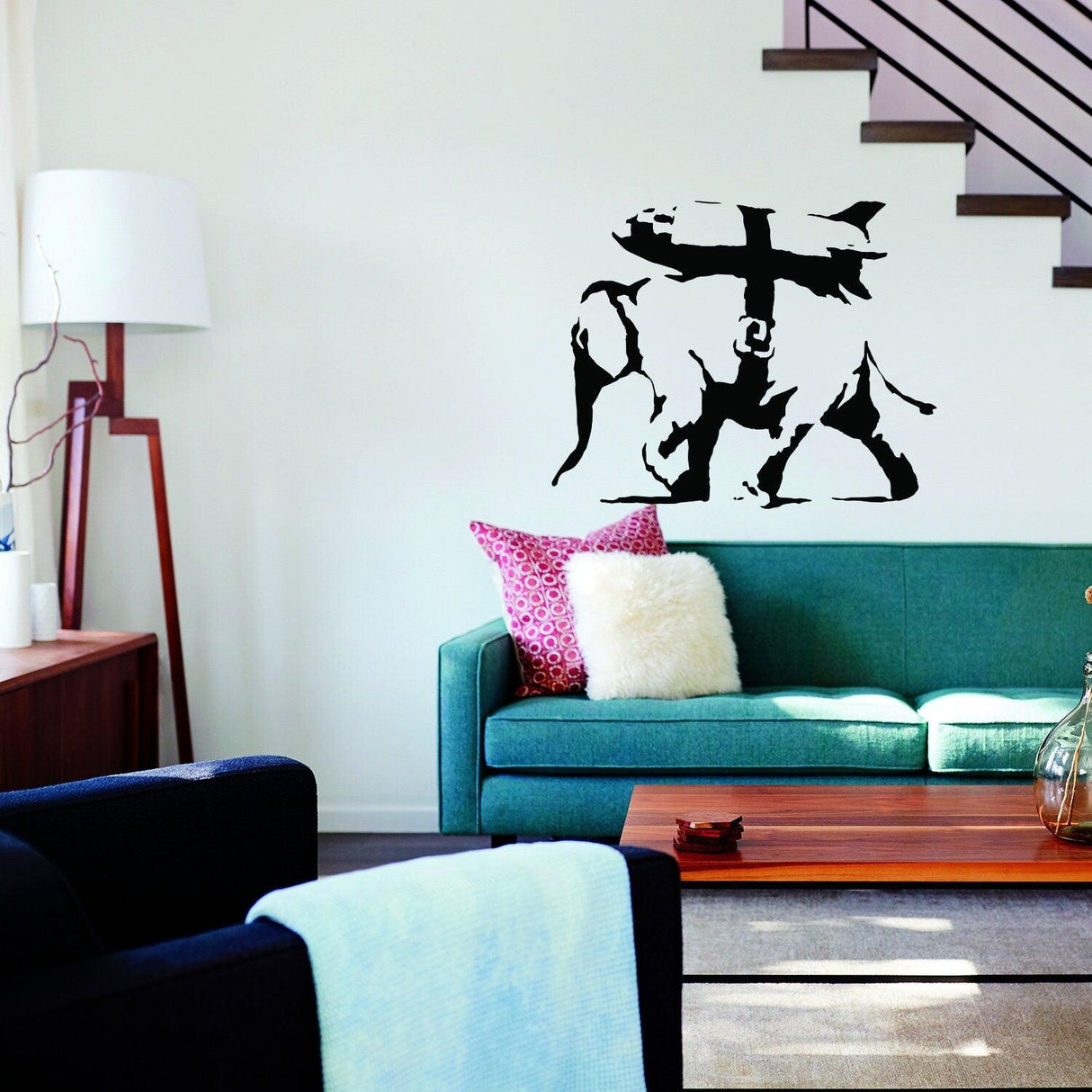 Banksy elephant bomb vinyl sticker displayed on a wall above a green sofa in a modern living room.