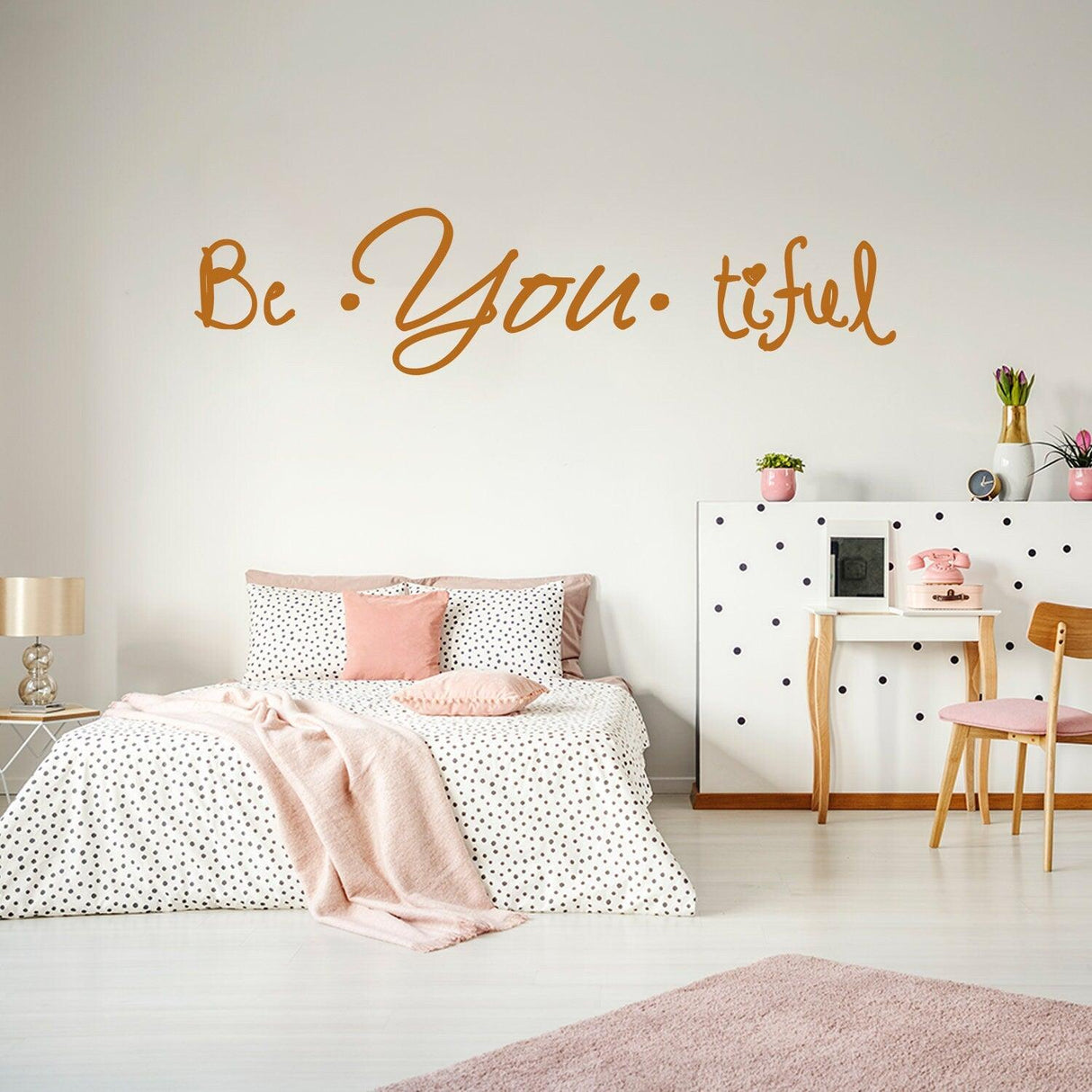 Beautiful quote wall sticker 'Be You-tiful' displayed in a stylish bedroom with pink and white decor.