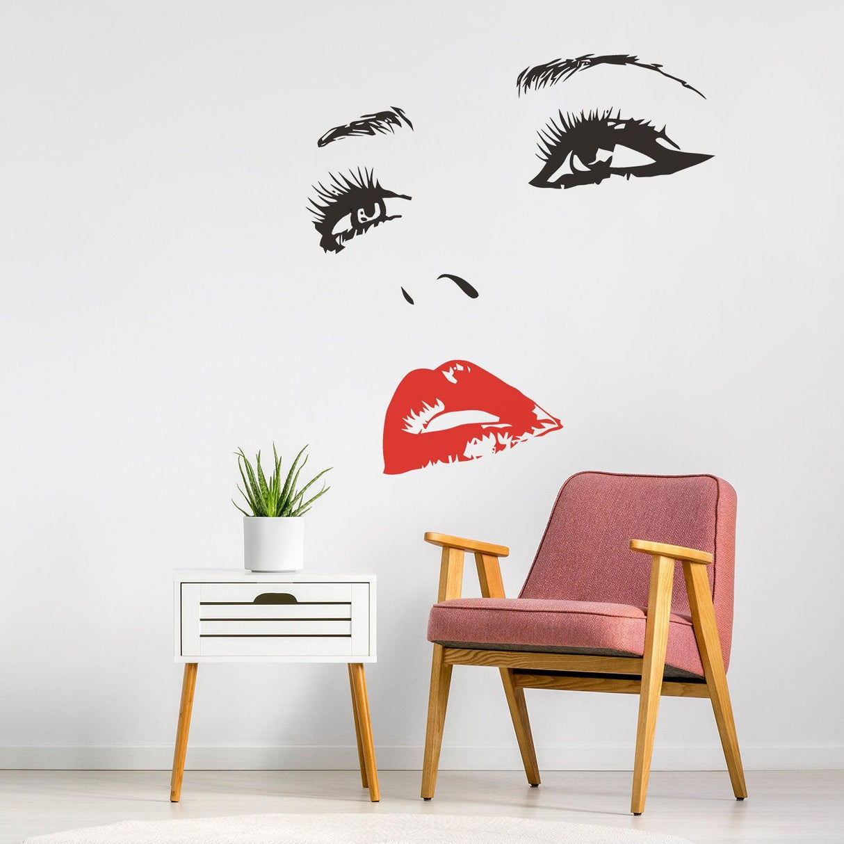 Elegant woman face vinyl wall decal in black and red above a pink chair, adding beauty and style to home decor.