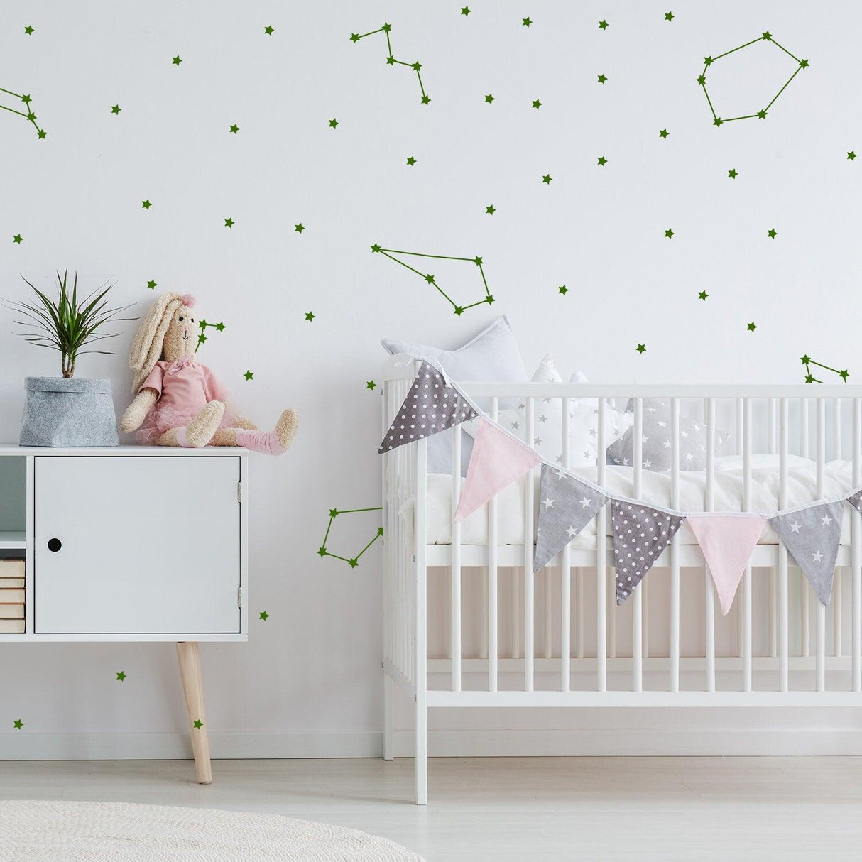 Room decorated with green constellation vinyl wall stickers and a cute crib, creating a celestial atmosphere.
