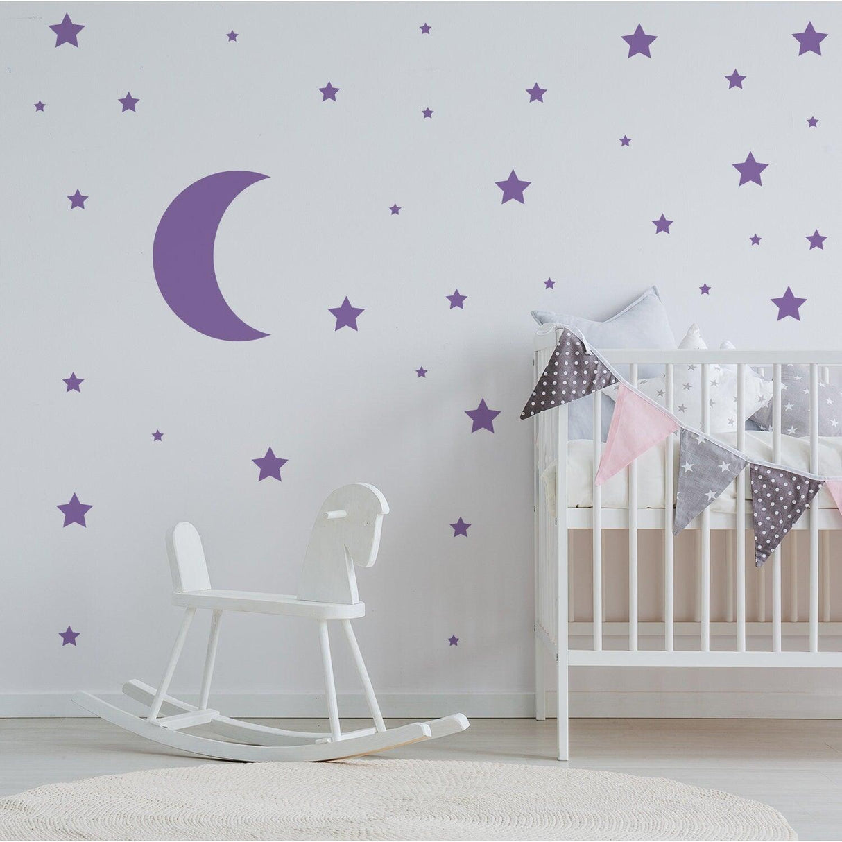 Purple star and moon wall stickers decorating a nursery with a rocking horse and crib.