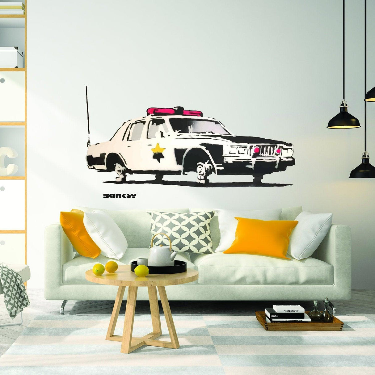 Police car vinyl sticker mural on wall above modern sofa in stylish living room with colorful cushions.