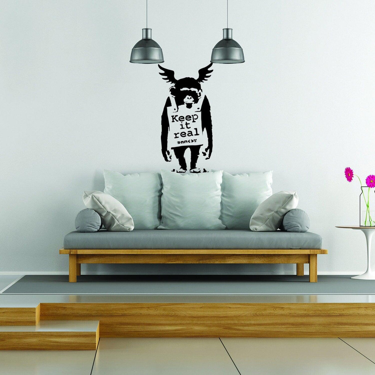 Banksy Keep It Real monkey wall decal above a stylish sofa in a modern living room setting.