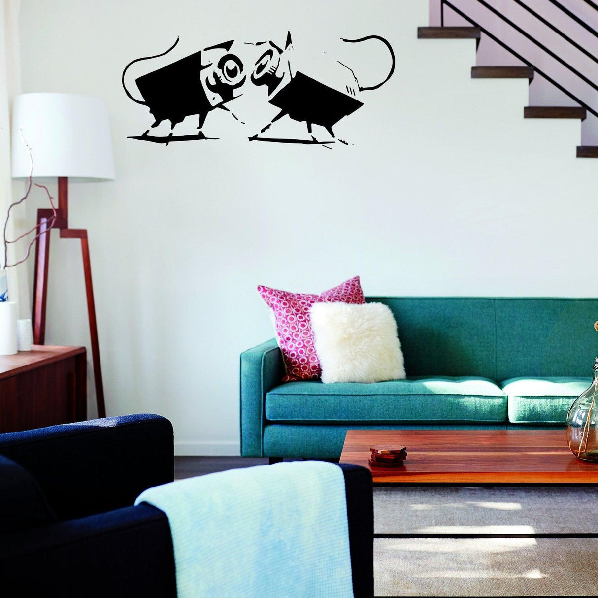 Banksy-inspired vinyl sticker of two cartoon rats facing each other on a living room wall above a green couch.
