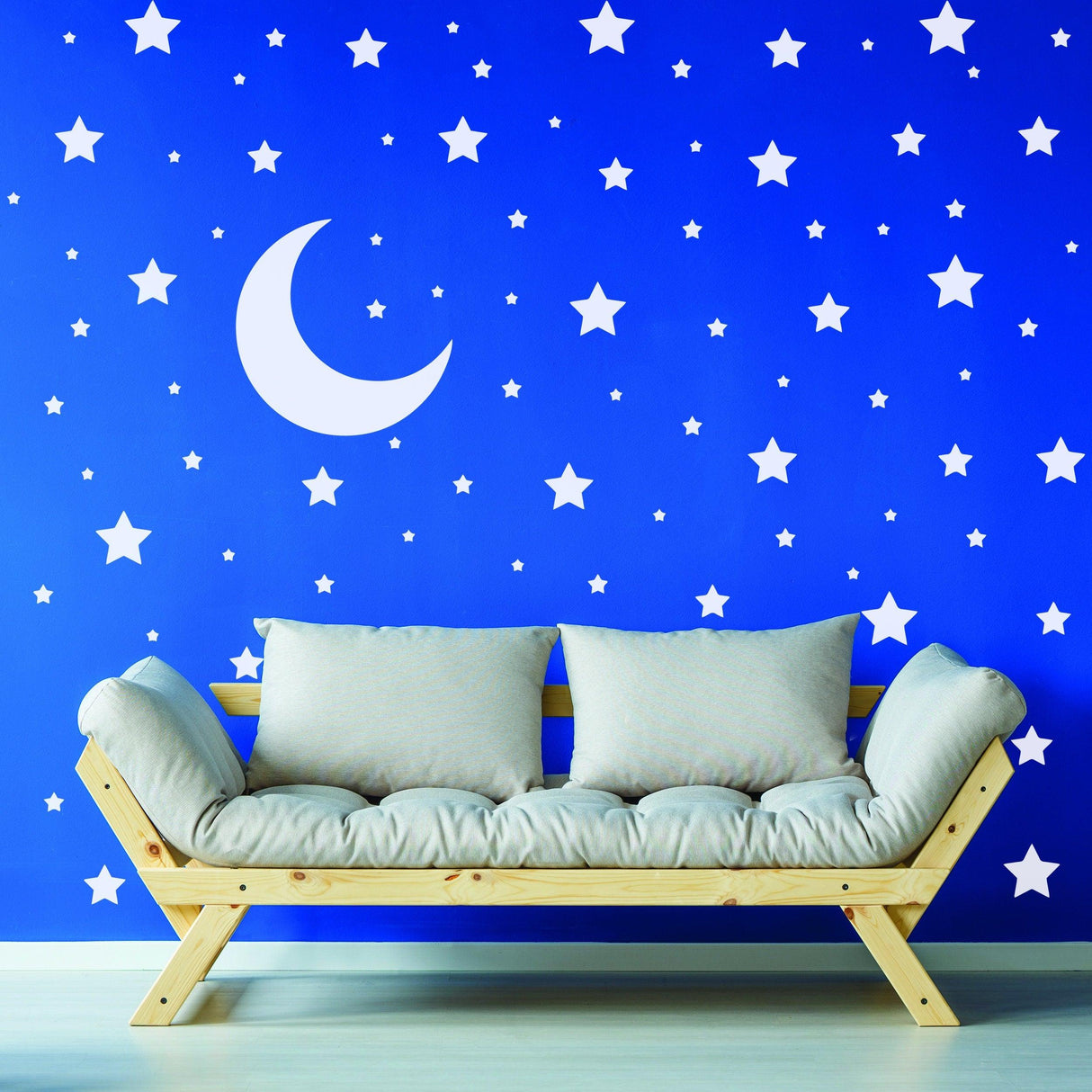 Wall with white stars and crescent moon decals above a cozy sofa, perfect for a child's nursery or kid's room.