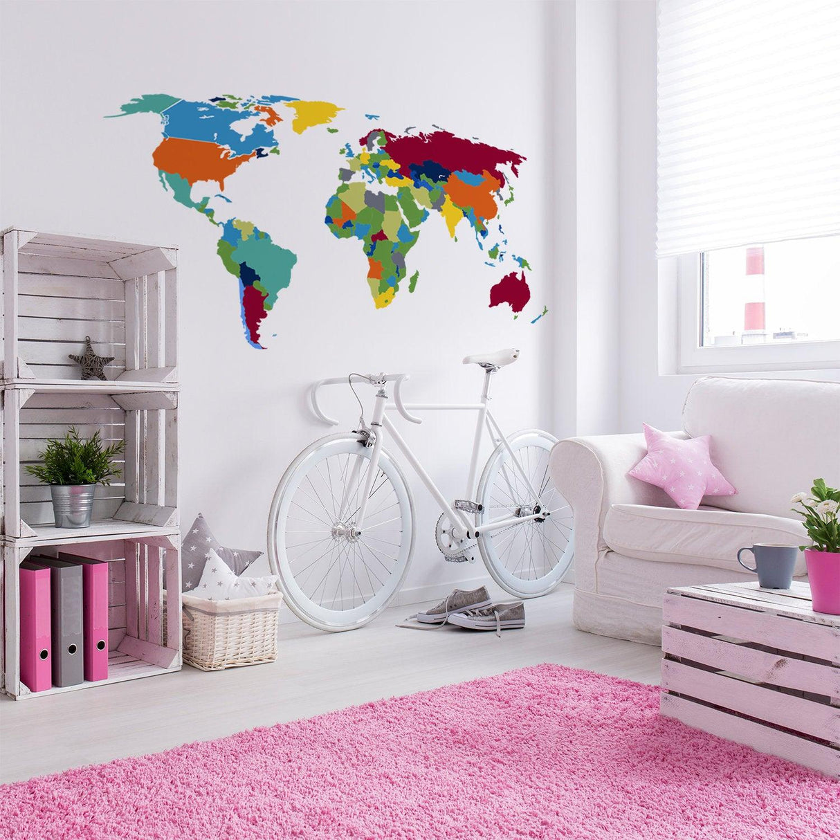 Large, colorful world map wall sticker in a modern living room with white bike and pink rug.