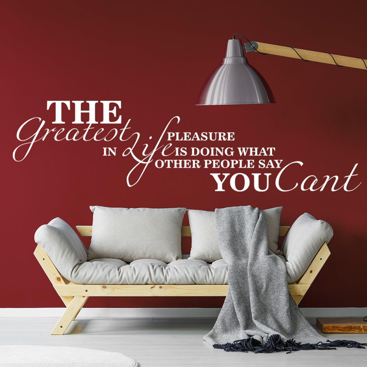 Wall quotes decal saying 'The Greatest Pleasure in Life is Doing What Other People Say You Can't' on living room wall.