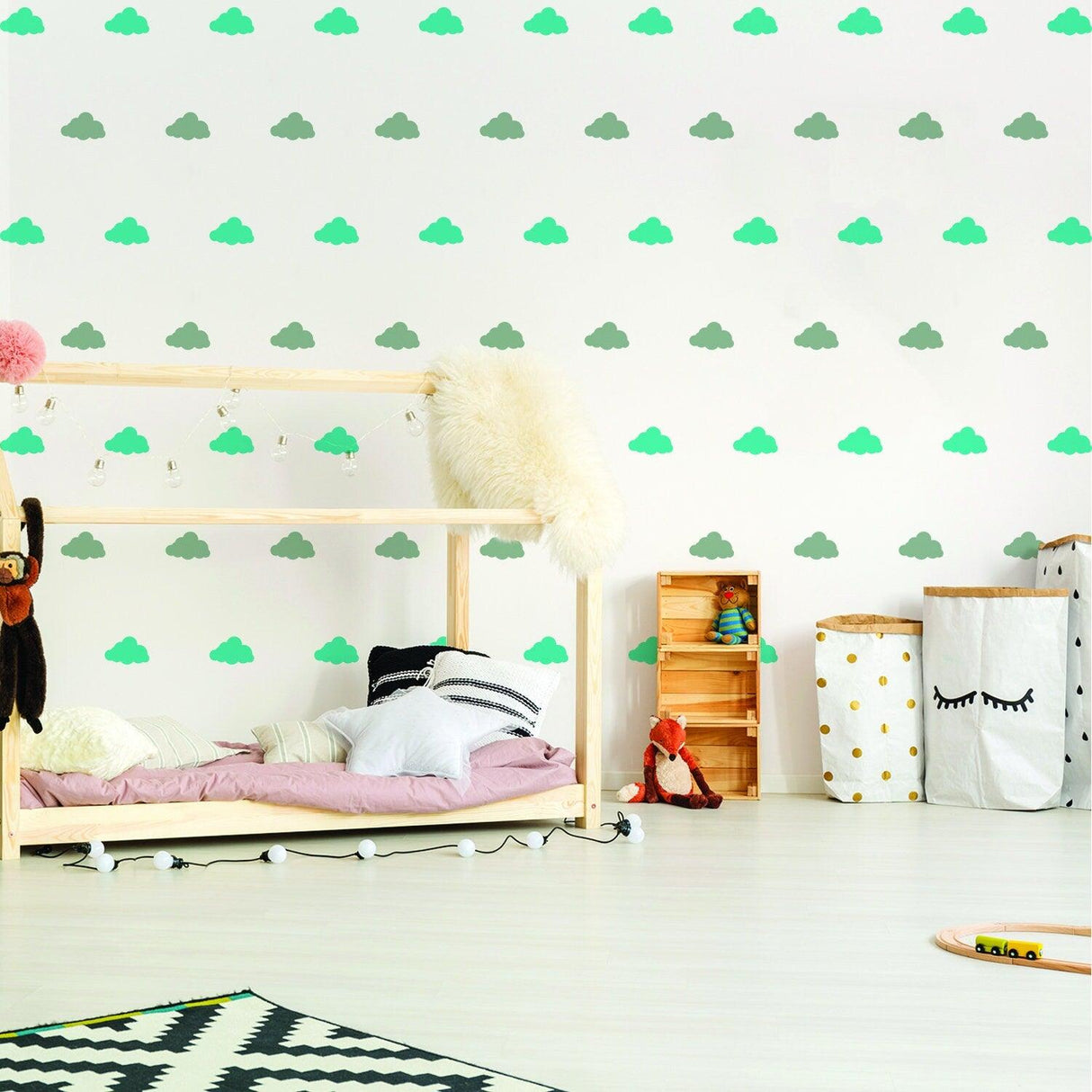 Colorful cloud wall decals in a nursery, featuring green and gray clouds on a white wall, enhancing baby room decor.