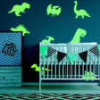 Glow in dark dinosaur wall decals in a boy's room, featuring various dinosaur designs around a crib.