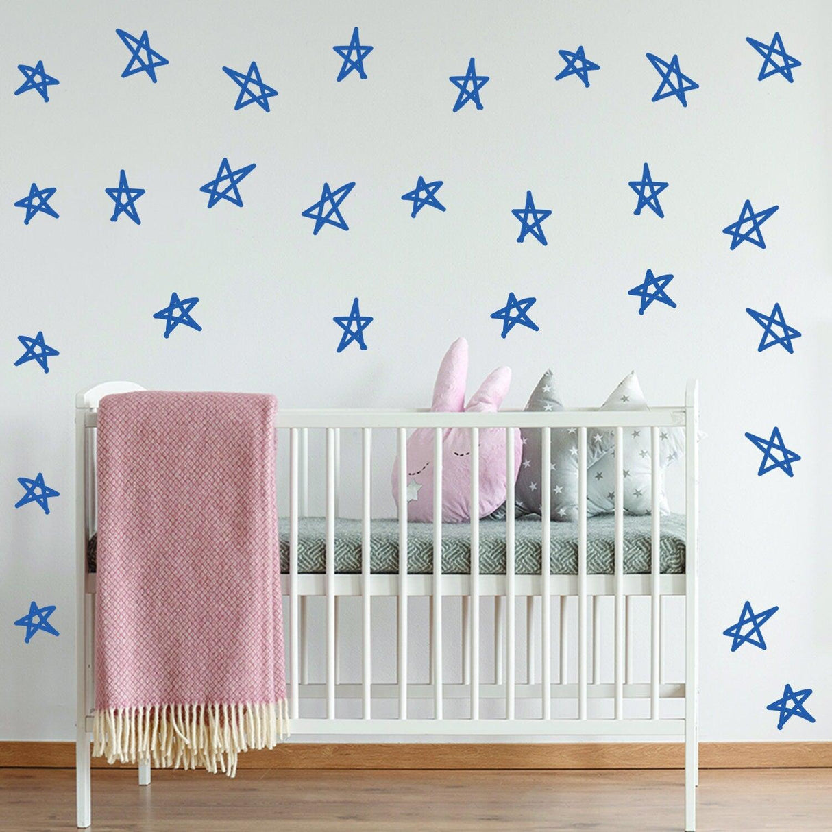 Blue star stickers on nursery wall with crib and plush toys, perfect for baby shower decor and twinkling ambiance.