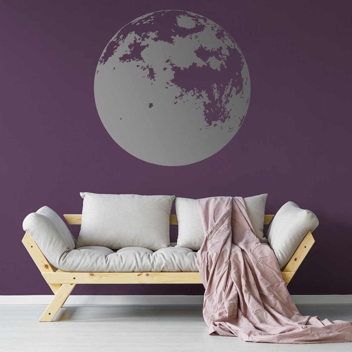 Moon phase wall decal on a purple wall above a cozy sofa with cushions and a throw blanket.
