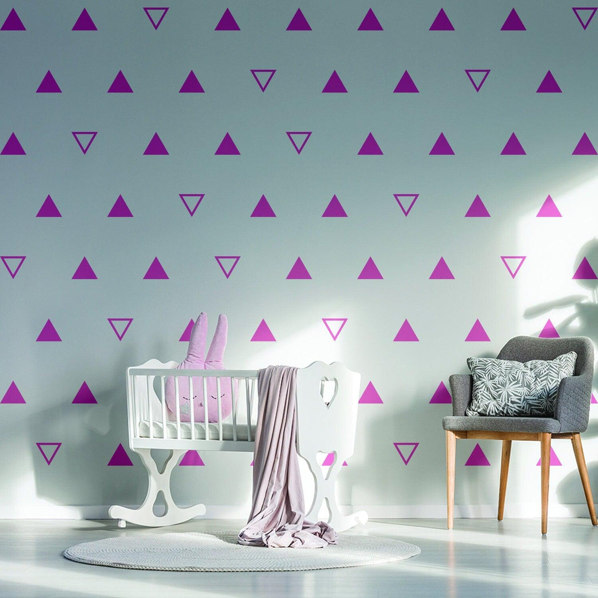 Nursery kids room with purple triangle vinyl decals on wall, featuring a crib and cozy chair.