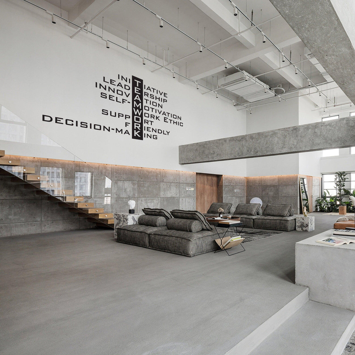 Modern office space with a Teamwork wall decal featuring motivational words and a cozy seating area.