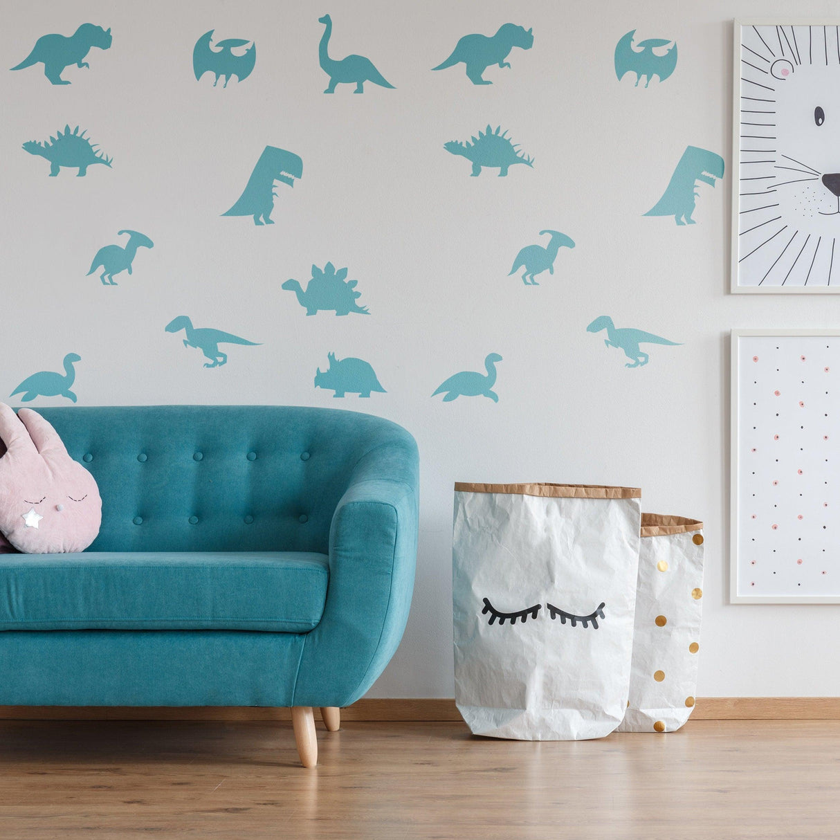 Blue dinosaur silhouette wall decals in a nursery, featuring various dinosaur shapes, alongside a teal couch and storage bins.
