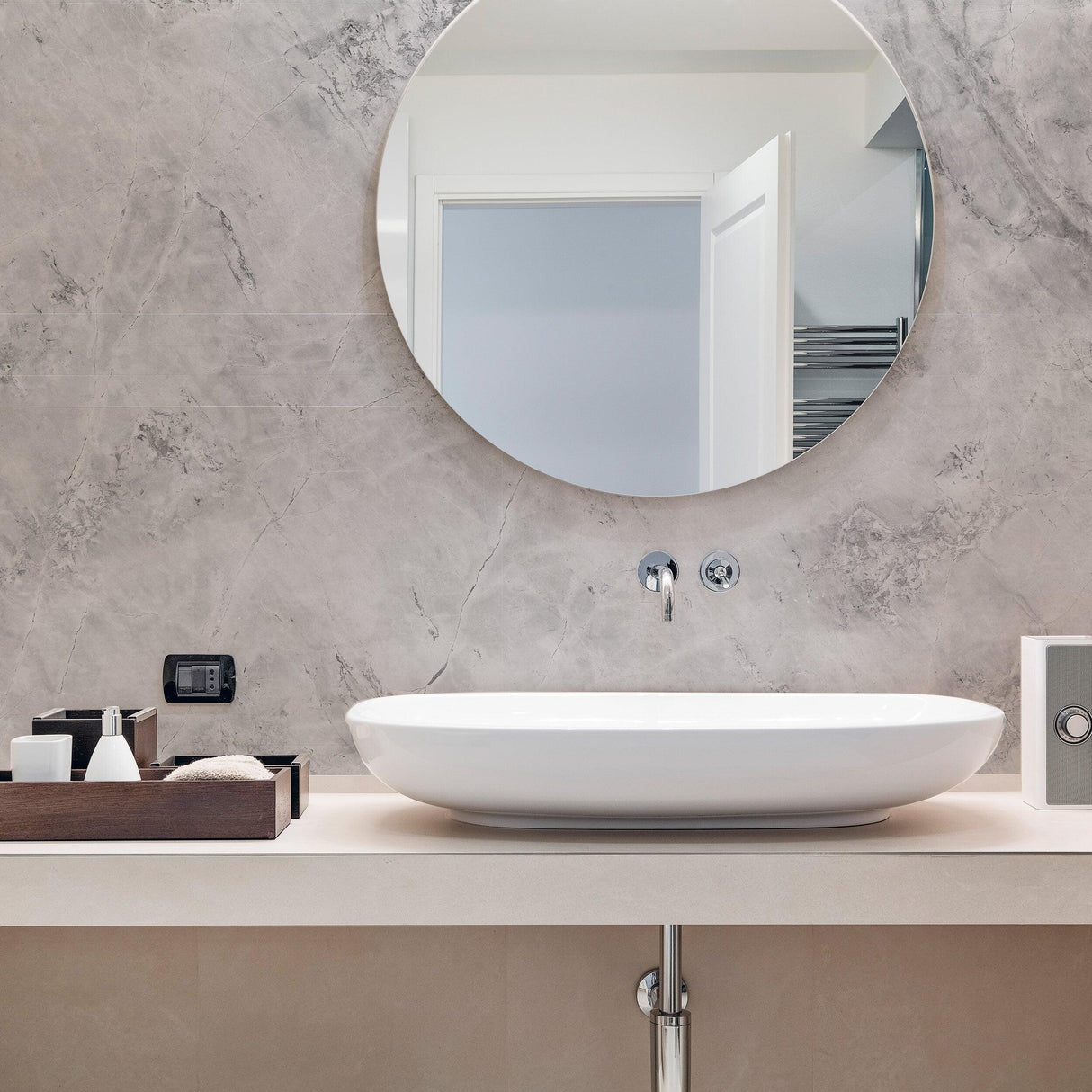Elegant bathroom featuring marble vinyl wallpaper, modern round mirror, and stylish white countertop with sink.