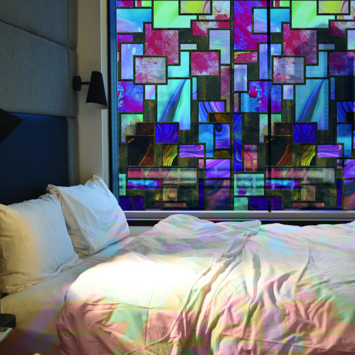 Colorful frosted glass film with geometric design covering a window in a cozy bedroom setting.