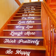 Staircase with vinyl quotes decals promoting positivity and family sayings on wooden stairs.