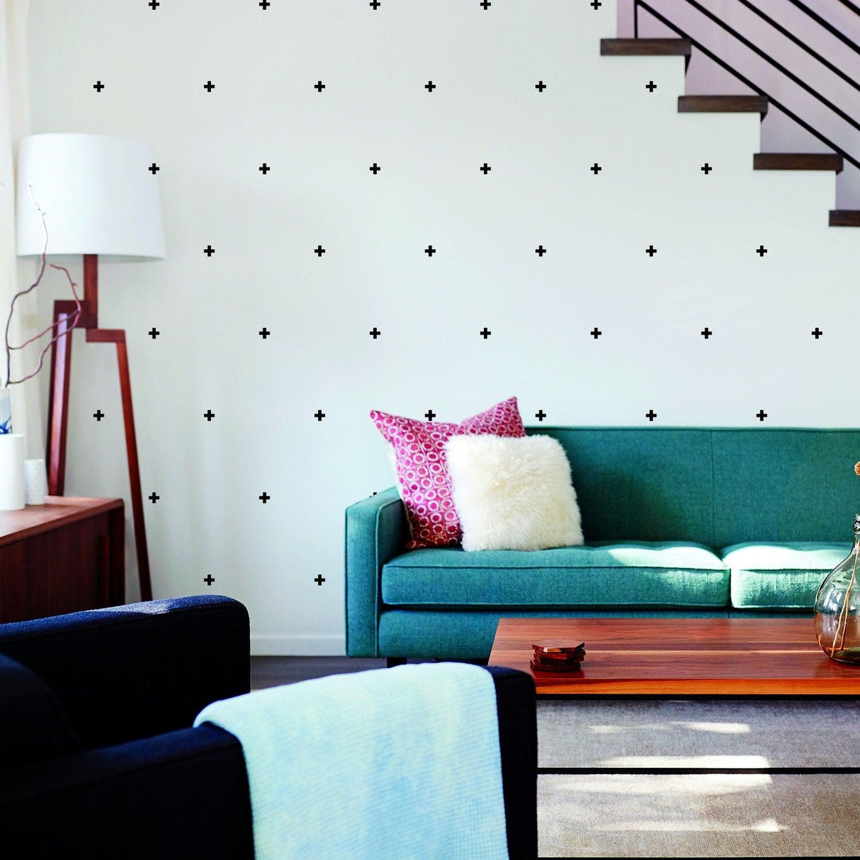 Vinyl wall decor featuring black cross stickers in a stylish living room with a green sofa and decorative pillows.