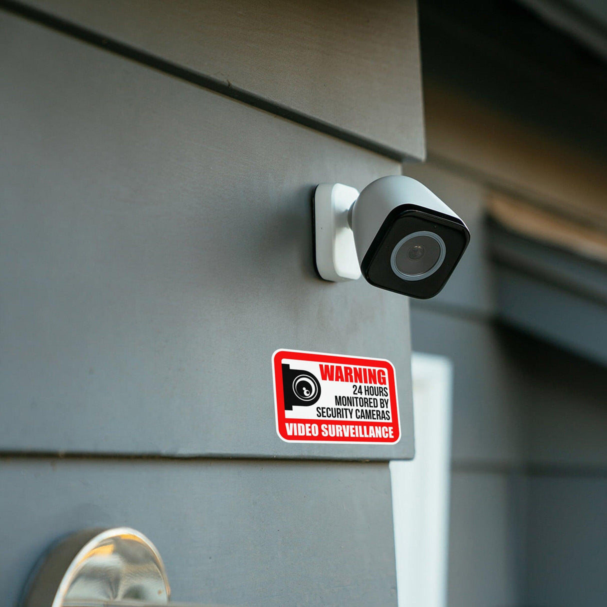 Video surveillance camera mounted on wall with warning sign for security monitoring.