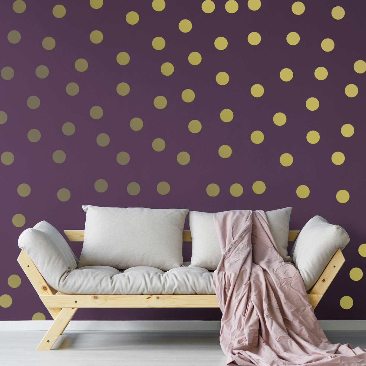 Stylish living room featuring gold circle wall stickers on a dark purple wall, complemented by a cozy sofa and blanket.