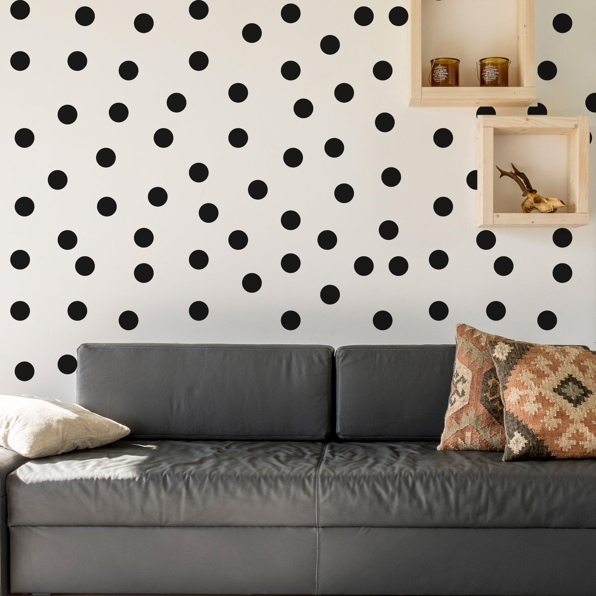 Living room featuring black circle wall stickers on a white wall, enhancing modern decor with a cozy sofa and patterned cushions.