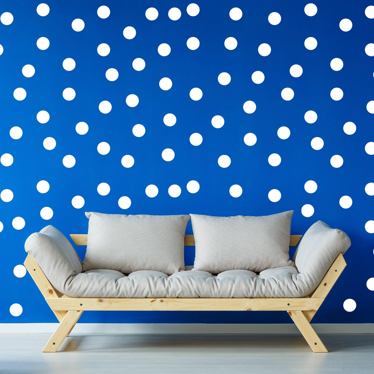 Living room with white circle wall stickers on blue wall and a modern wooden sofa.