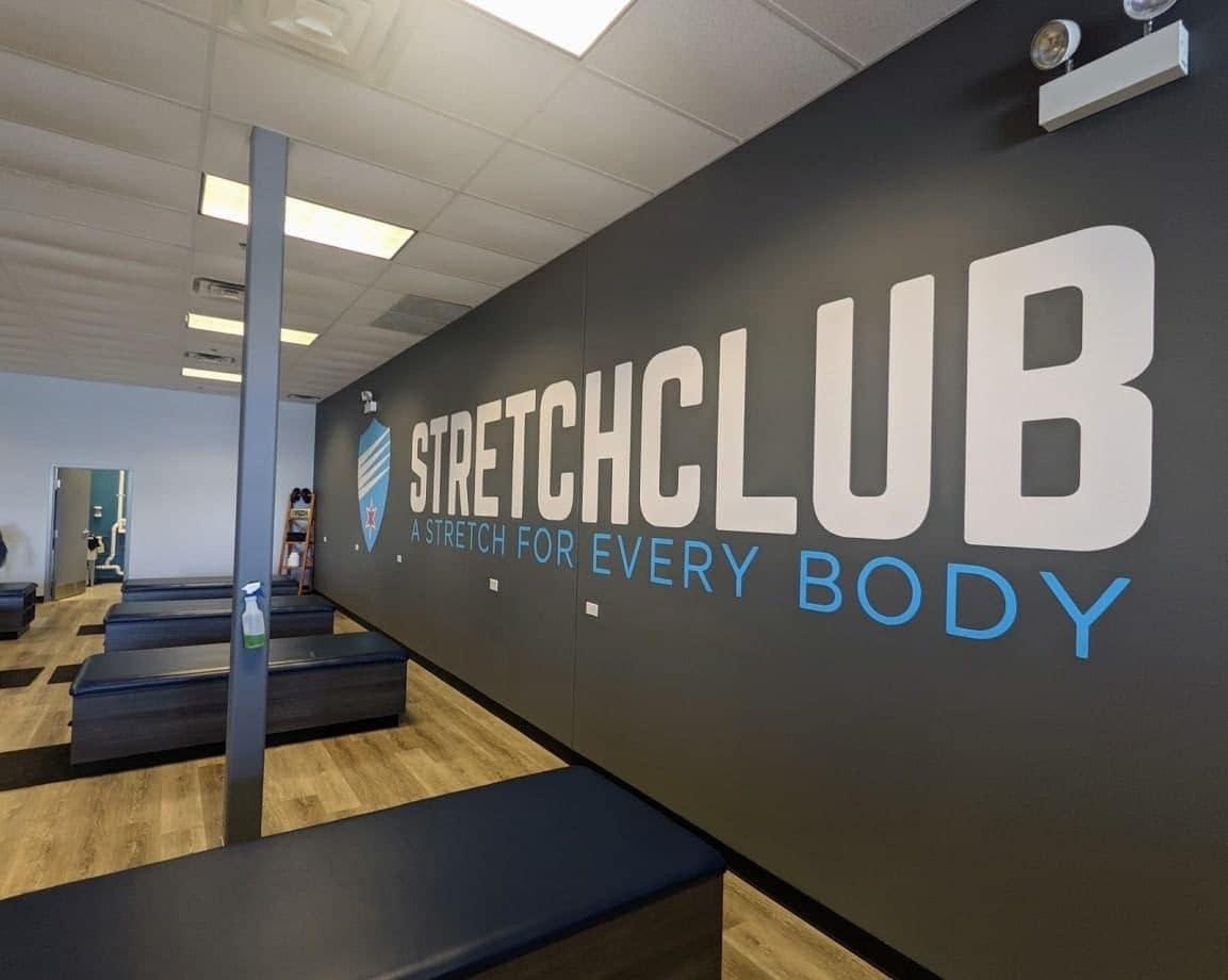 Interior of Stretch Club with logo on wall and stretch tables set up for clients.
