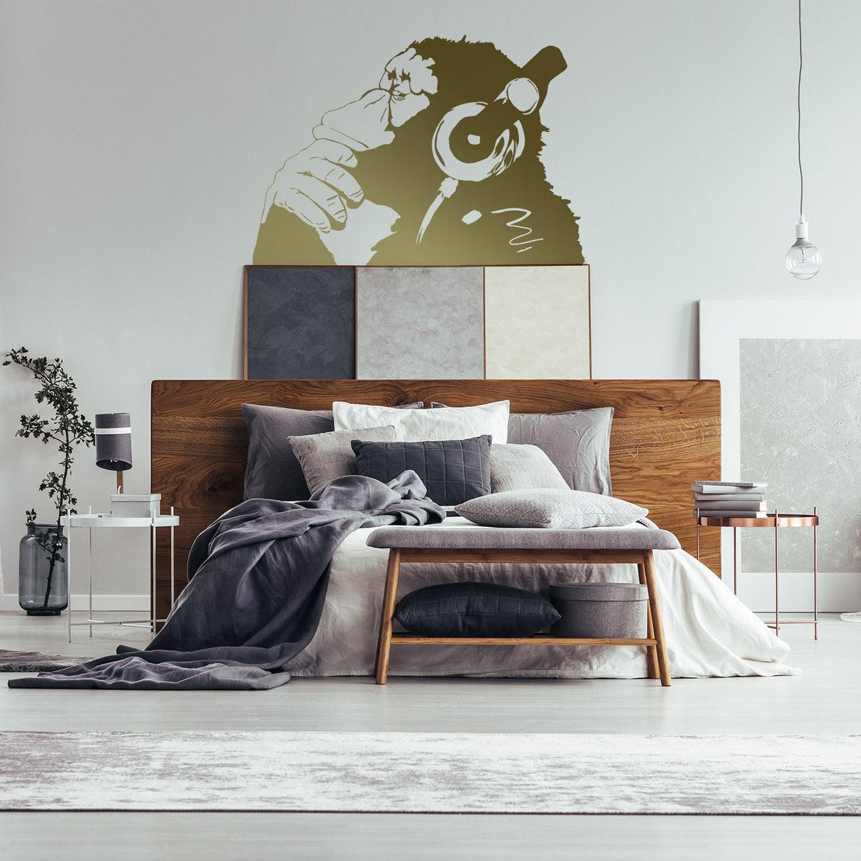 Banksy monkey with headphones wall sticker above a stylish bed in a modern bedroom decor.