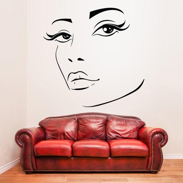 Woman eyes sticker wall decor above a red couch, adding elegance to the living room.