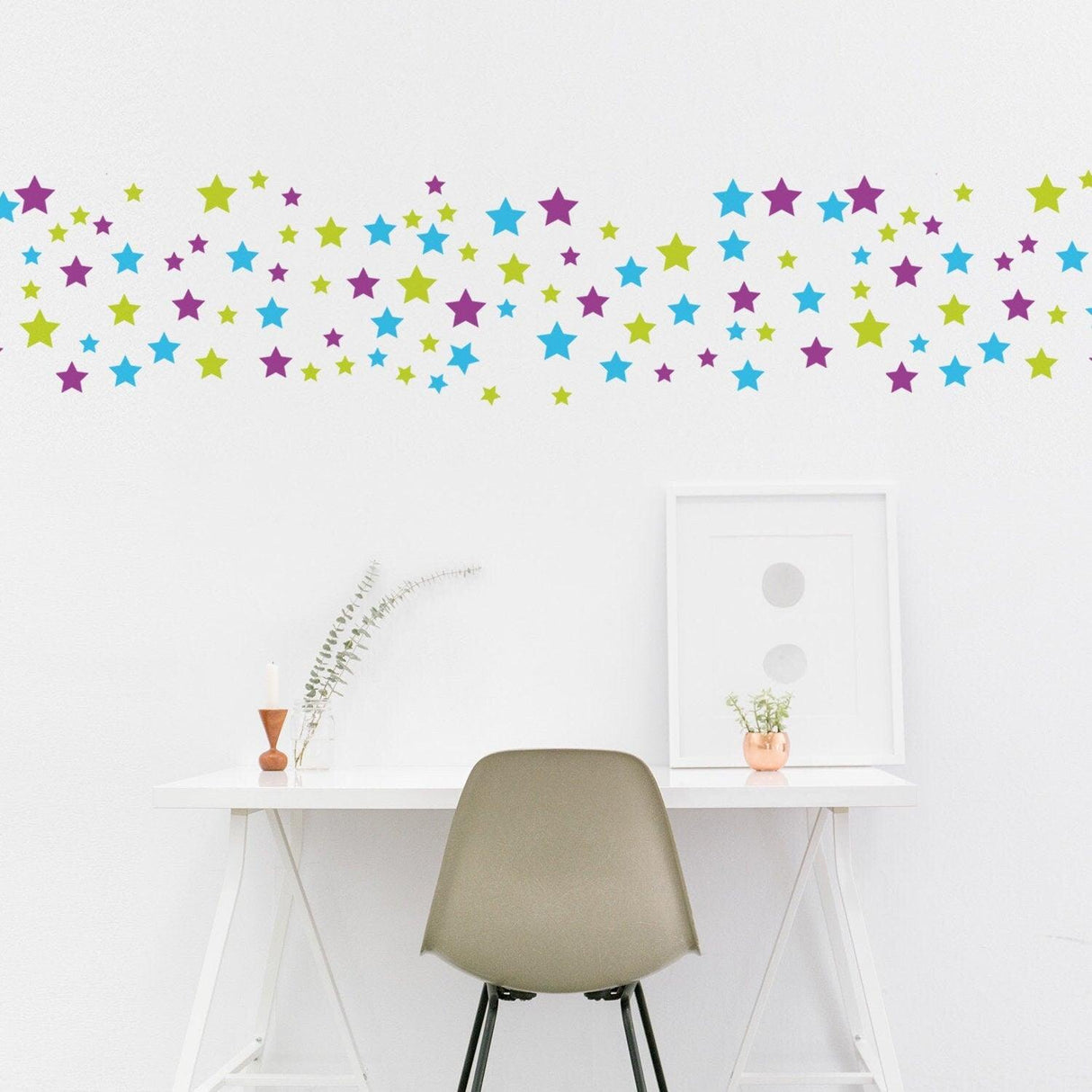 Colorful stars wall decals in green, blue, and purple above a modern nursery desk, creating a whimsical atmosphere.
