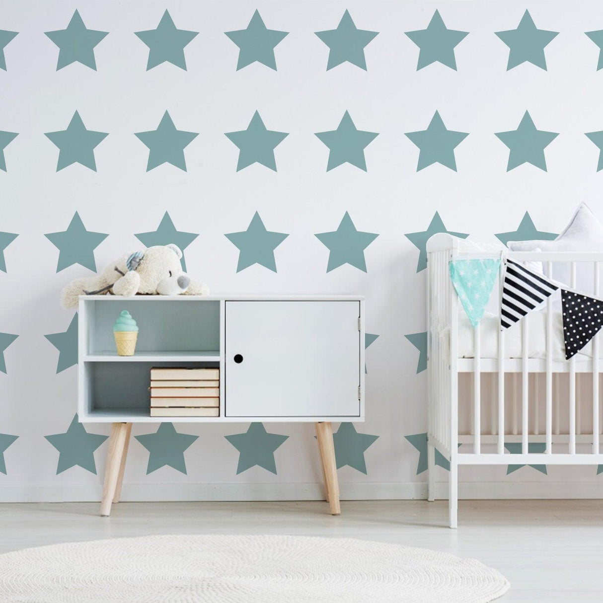 Nursery featuring removable star wall decals, a crib, and stylish storage unit for children's decor.