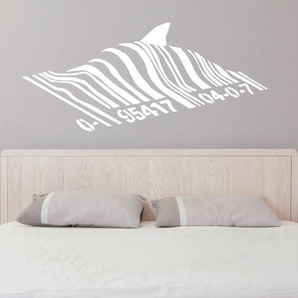 Banksy Barcode Shark wall vinyl sticker glowing design on gray wall above a bed, perfect for kids' room decor.