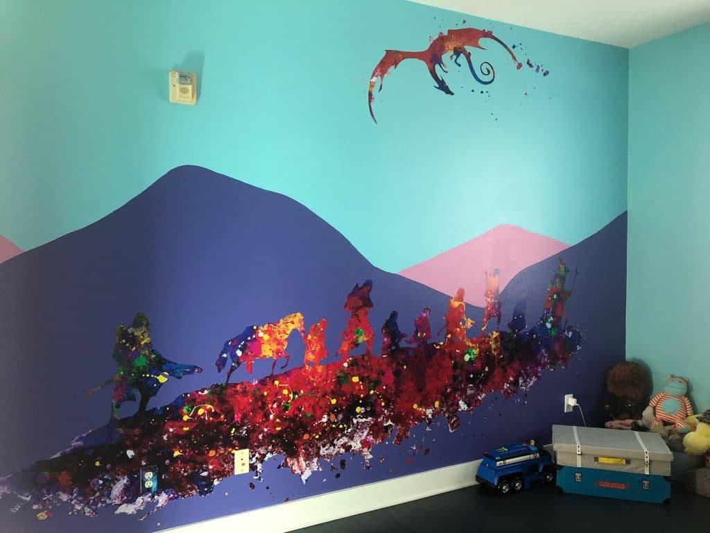 Colorful mural of a whimsical landscape featuring mountains, a dragon, and playful figures on a vibrant wall.
