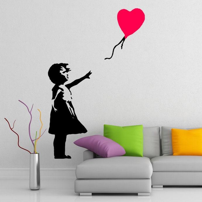 Banksy Girl With The Red Balloon wall decal in modern living room with colorful pillows and vase.