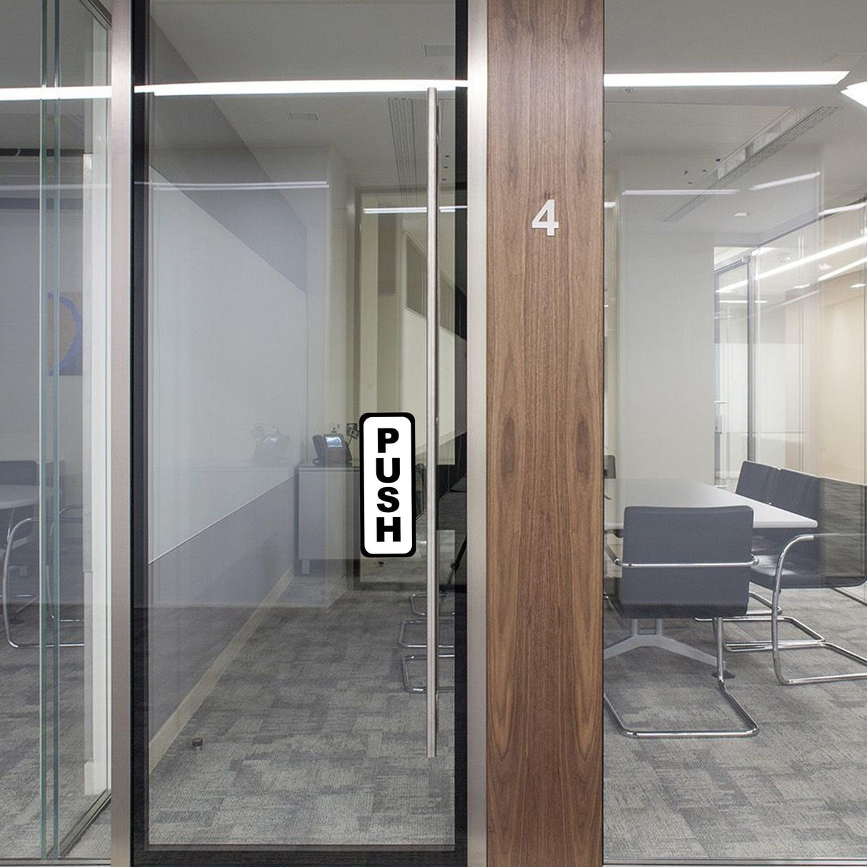 Vertical 'PUSH' sign on glass door in an office, guiding visitors on door action.