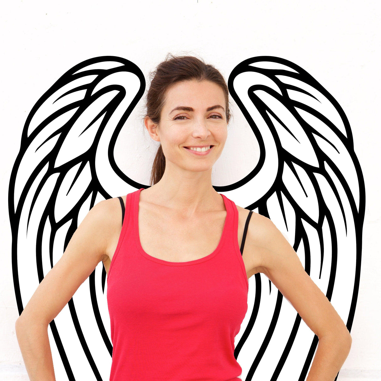 Woman smiling in front of angel wings wall decor vinyl decal, showcasing elegance and beauty in home decor.
