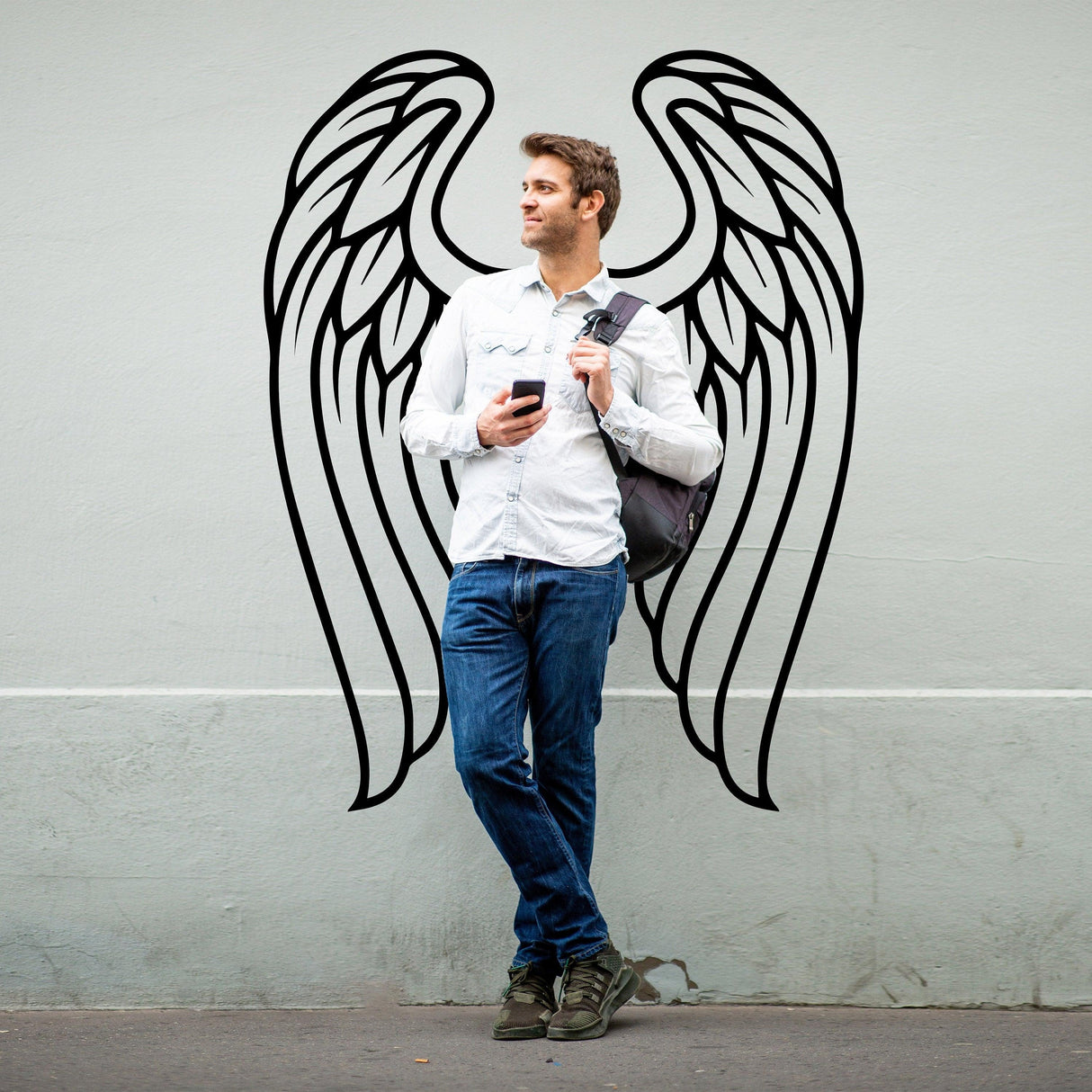 Man standing against a wall with angel wings vinyl decal, showcasing elegance and beauty in decor.
