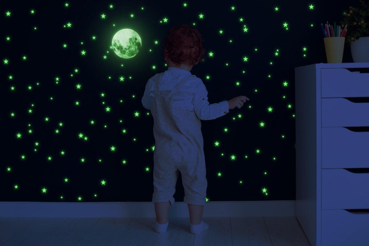 Child admiring glow in the dark stars and moon wall stickers in a cozy bedroom setting.