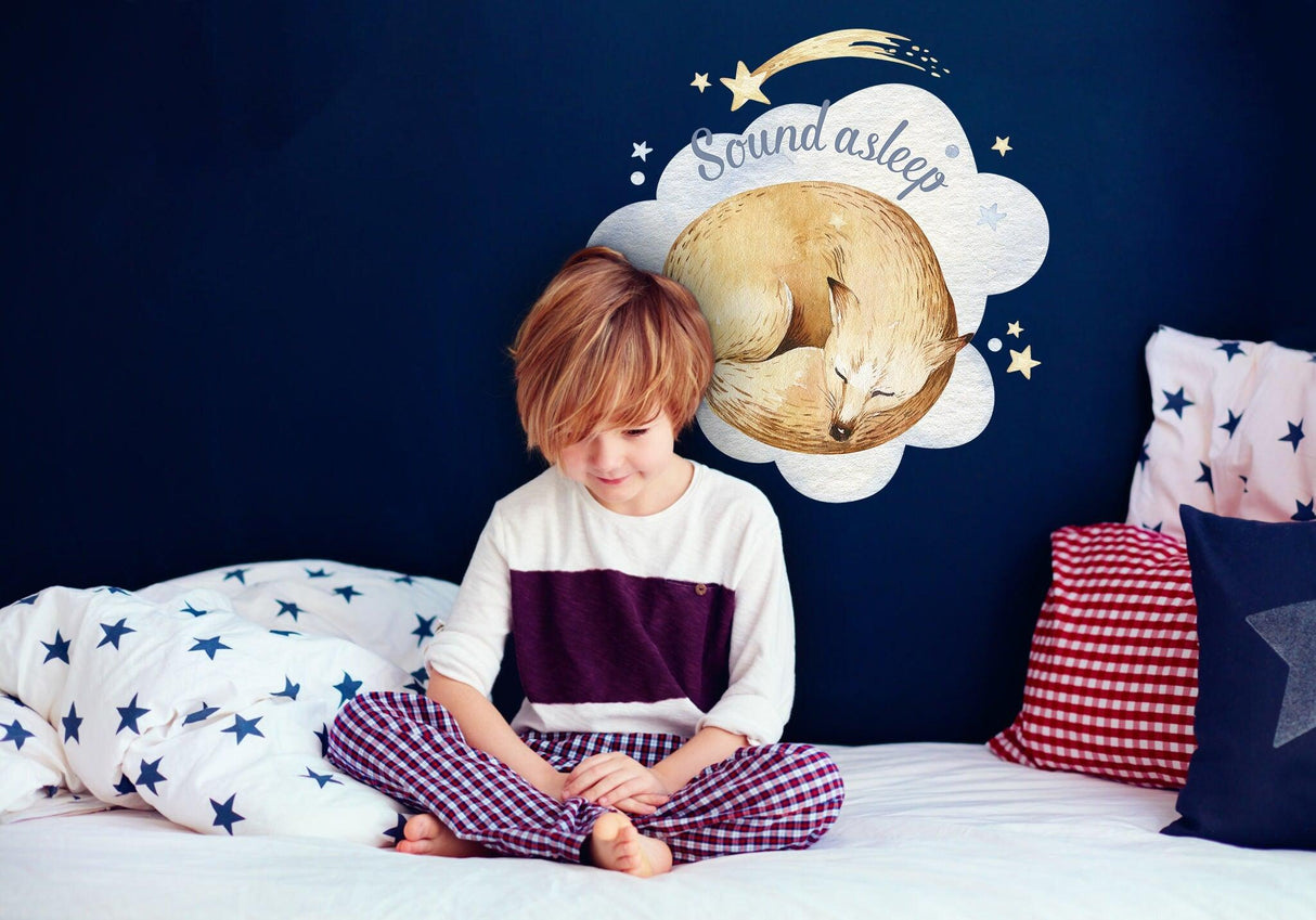Child sitting in bed with 'Sound asleep' wall decal featuring a sleeping fox, adding charm to a nursery.