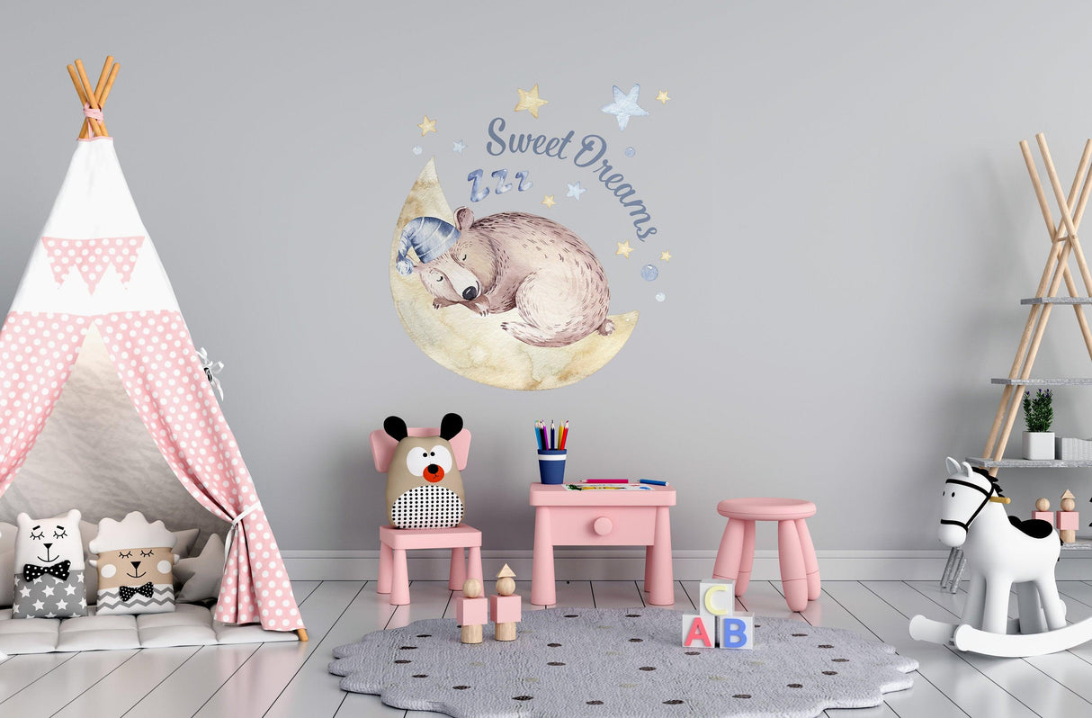 Cute sleeping animal wall sticker with 'Sweet Dreams' text in a nursery with pastel decor and playful furniture.