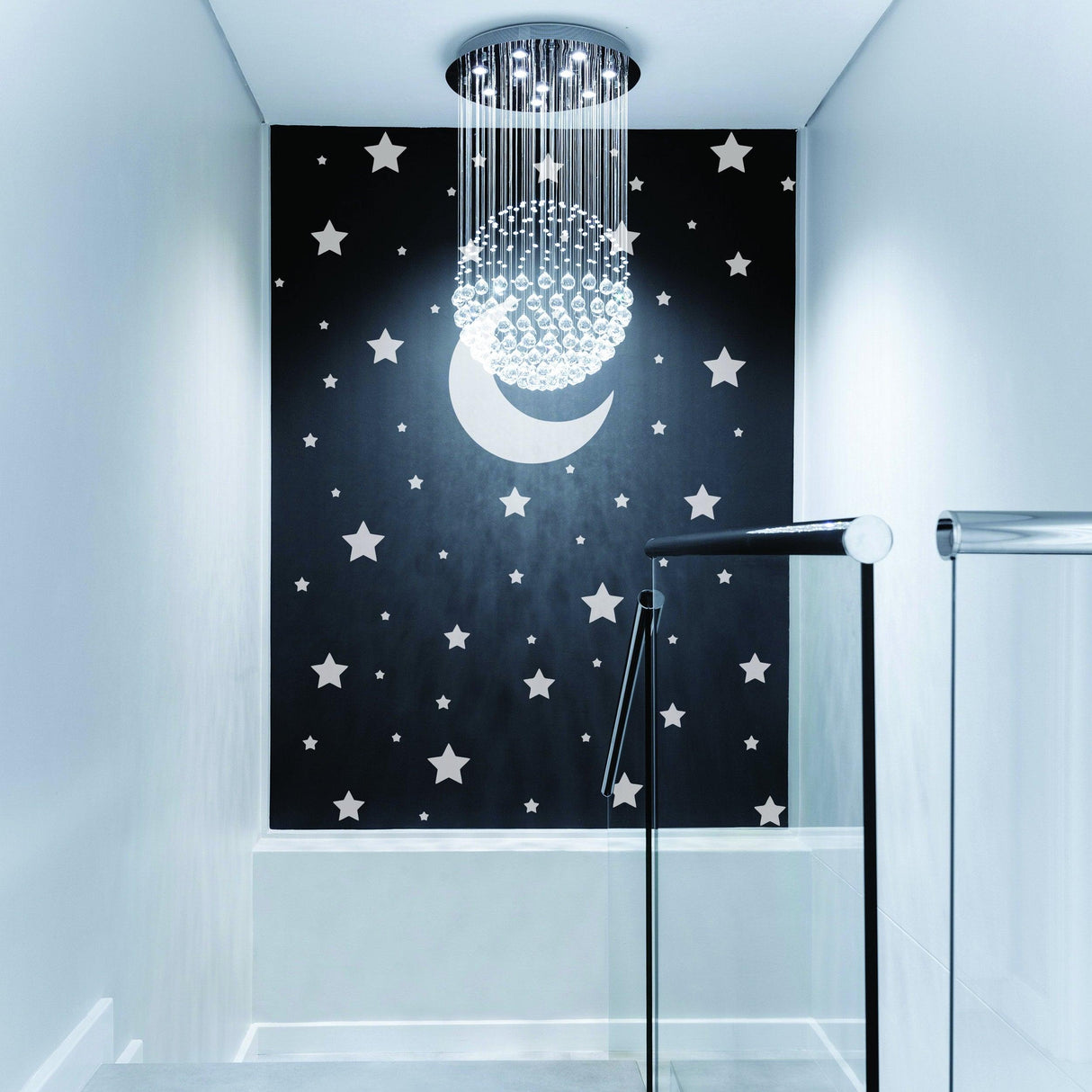 Stylish nursery with black wall covered in gold and silver star decals and a crescent moon, featuring a modern chandelier.