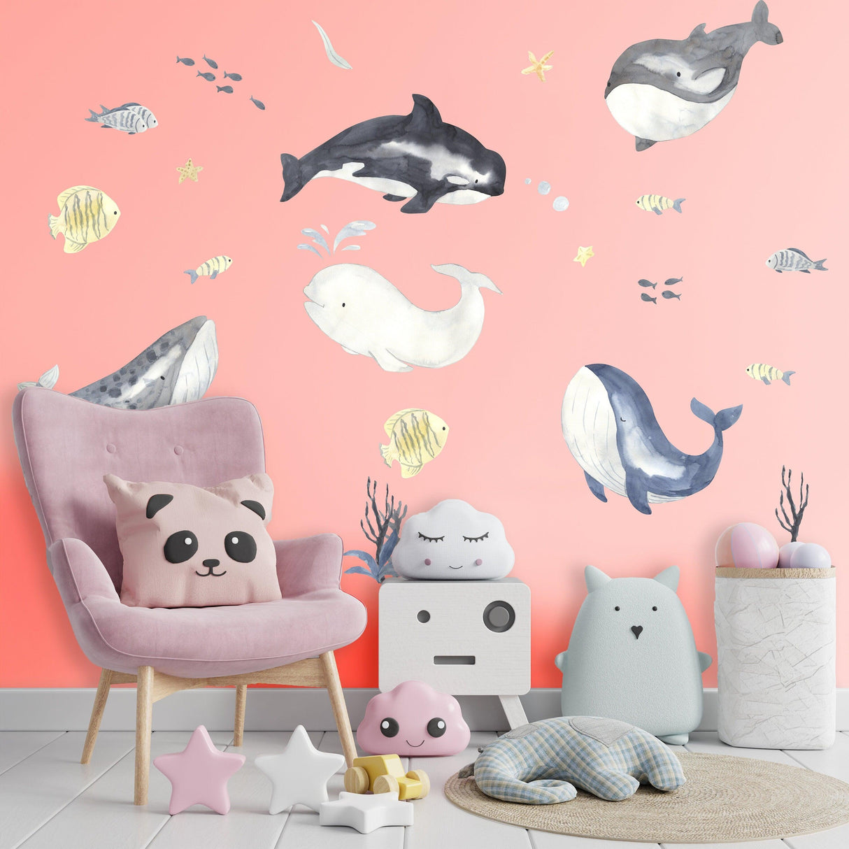 Colorful sea whales wall sticker in a child's room with coral background, soft toys, and a cozy chair.