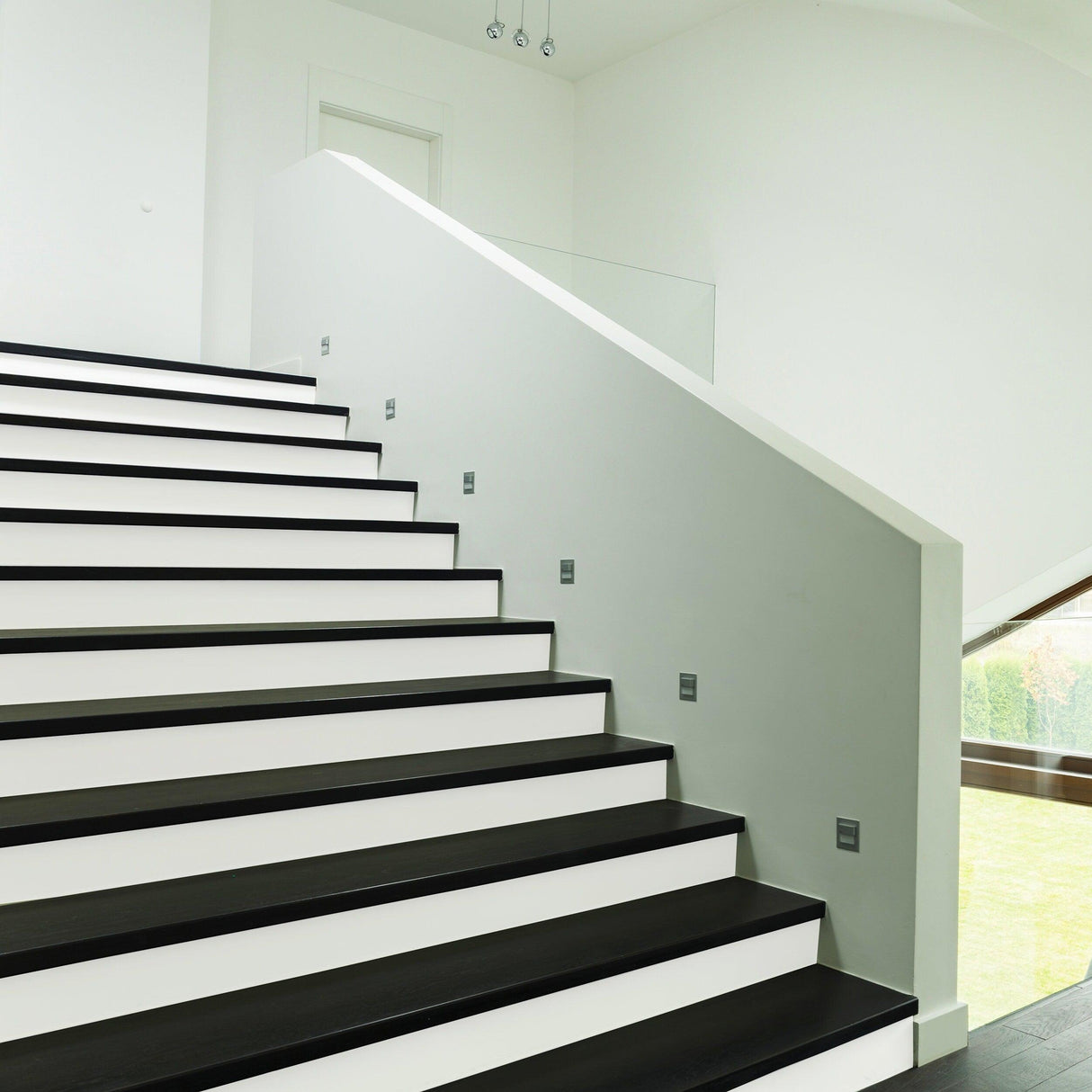 Modern staircase showcasing black steps with white risers, featuring sleek design and stylish LED lights.