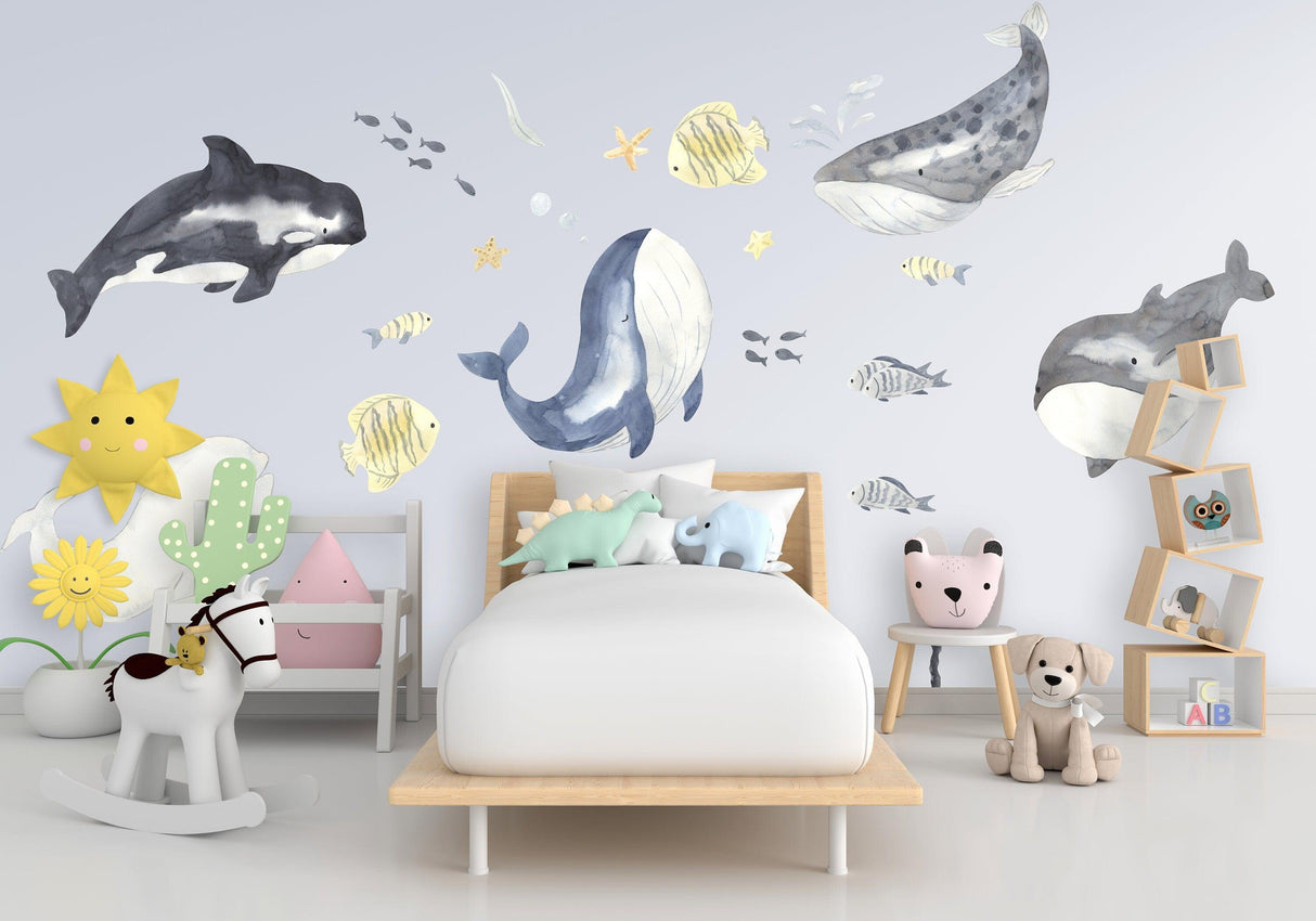Colorful sea whales wall stickers in a child's room with playful decor and soft toys, ideal for nursery design.