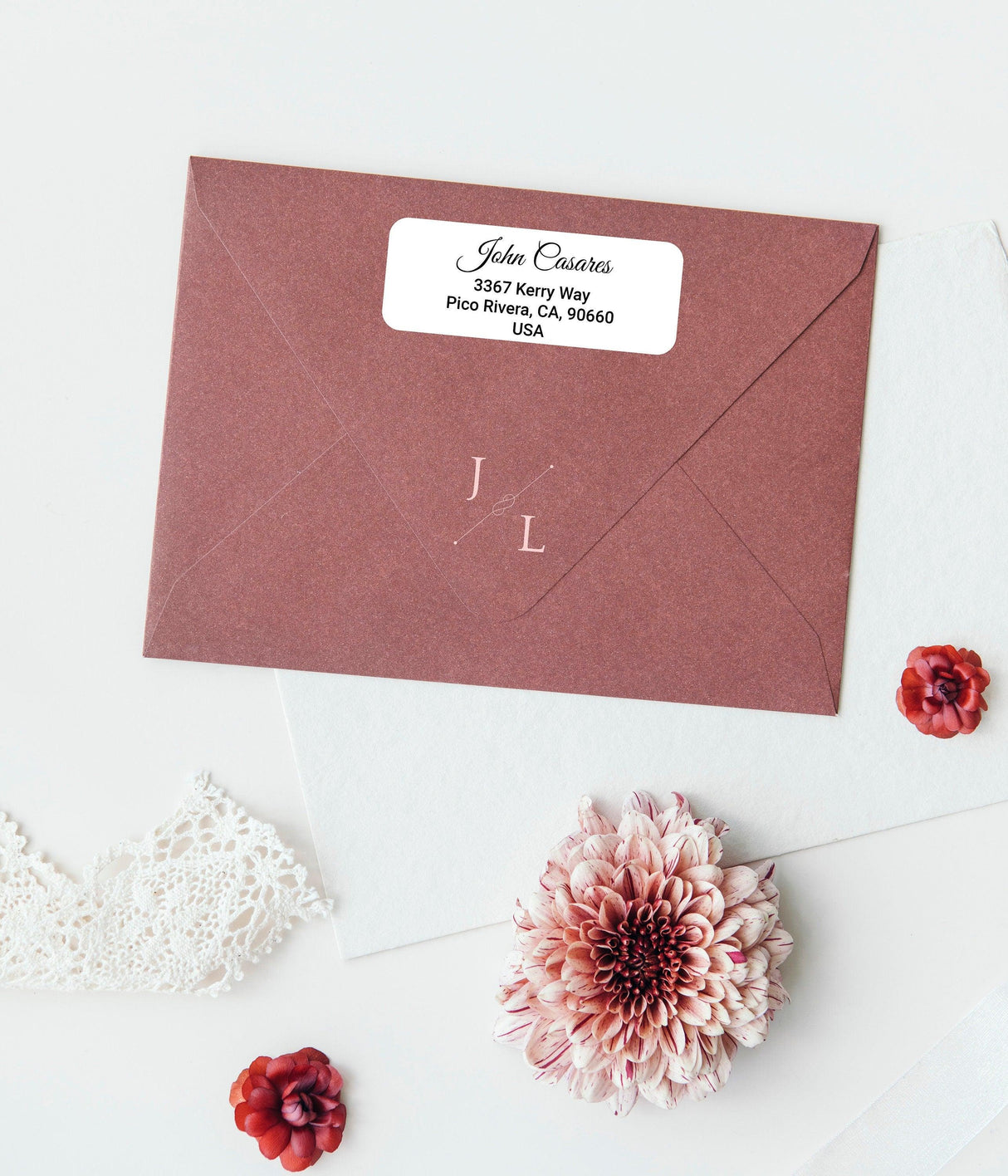 Personalized return address label on a stylish maroon envelope with floral accents and custom text.
