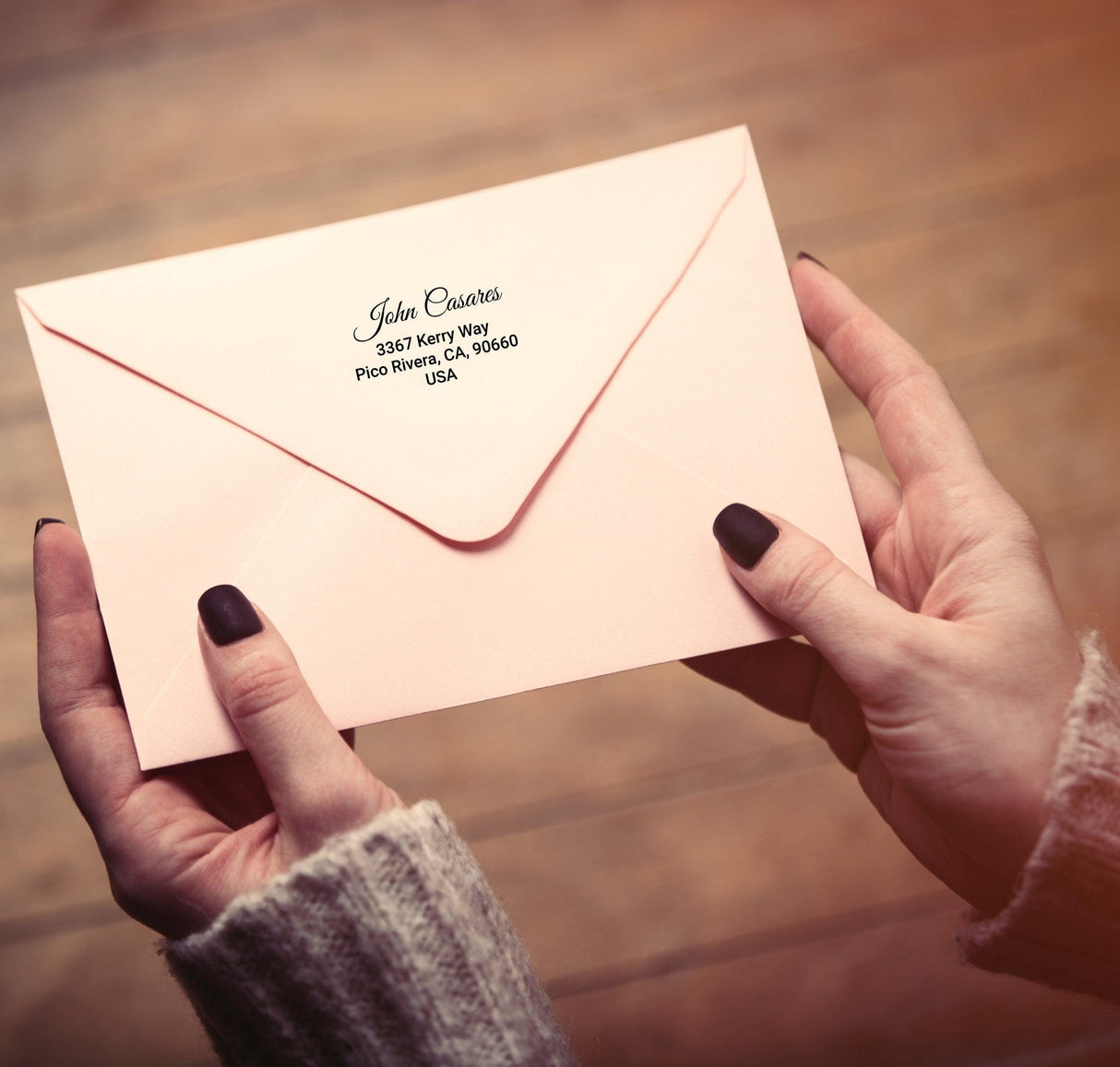 Personalized return address label on a pale pink envelope held in hands, showcasing custom mailing stickers.