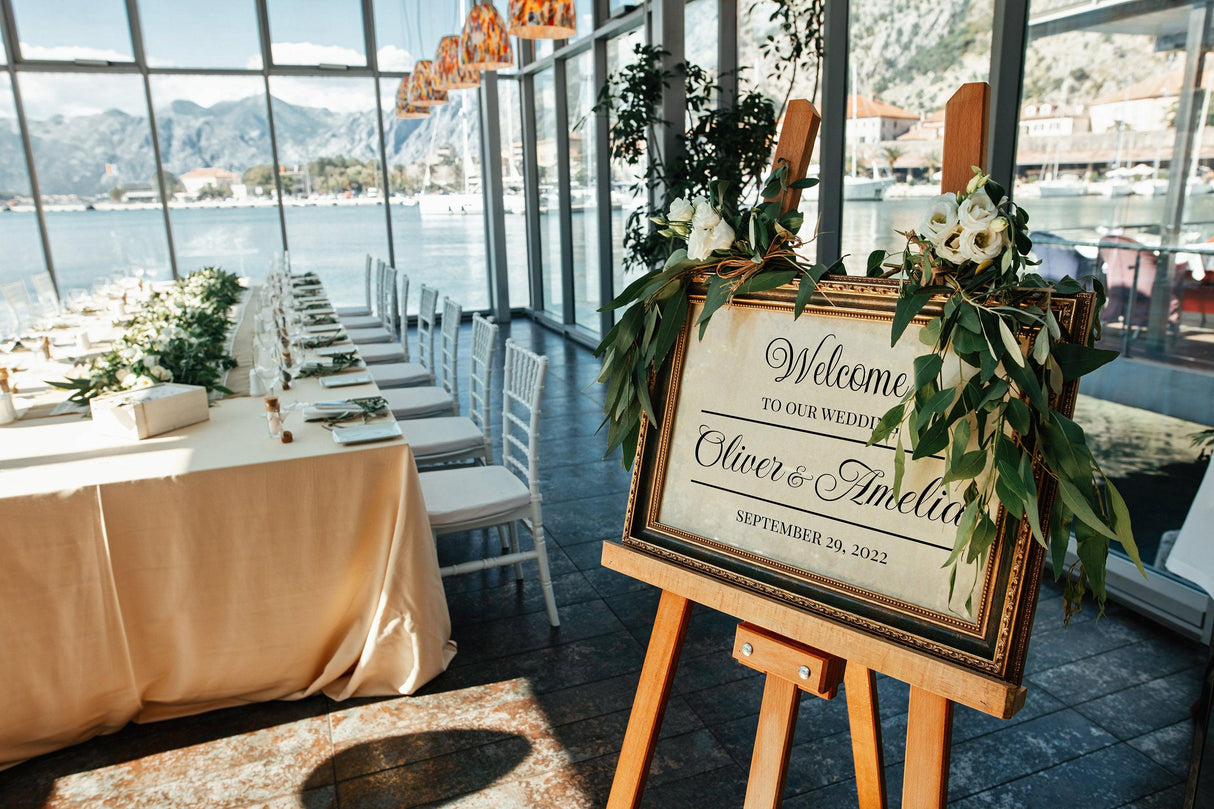 Personalized wedding welcome sign with Oliver & Amelia's names and date, elegantly decorated with greenery.